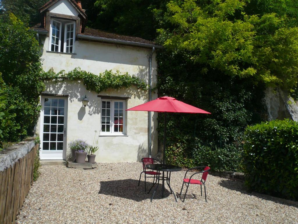 a table and chairs with an umbrella in front of a house at LA PONCÉ SECRÈTE in Poncé sur Le Loir