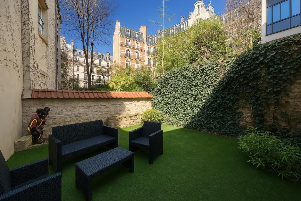 une cour avec 2 chaises et de la pelouse verte dans l'établissement Garden flat in Paris 16, à Paris
