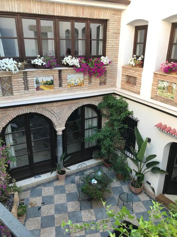 a building with a courtyard with potted plants and windows at La casa del Retablo in Córdoba