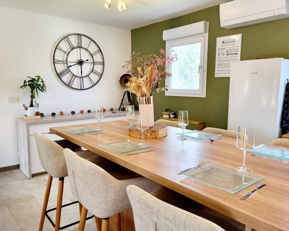 une salle à manger avec une table en bois et une grande horloge dans l'établissement Villa L'Elsy avec Jardin Proche Vogüé et Aubenas, à Saint-Sernin