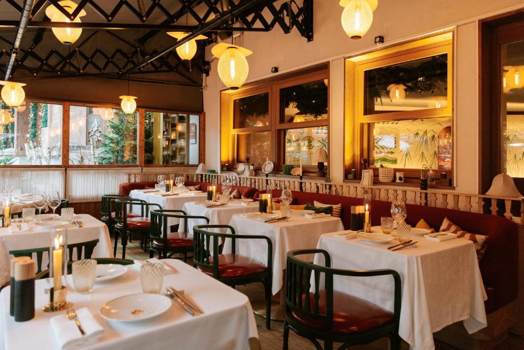 a restaurant with white tables and chairs and lights at Coeur de Megève in Megève
