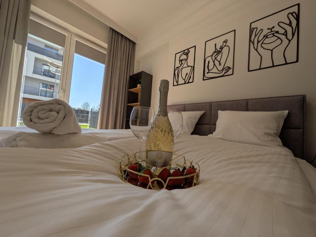 una bottiglia di vino e un cesto di frutta su un letto di Magic Apartments - Zibi a Zator