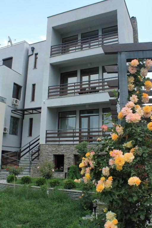 a white building with flowers in front of it at Family Hotel Stumari in Tbilisi City