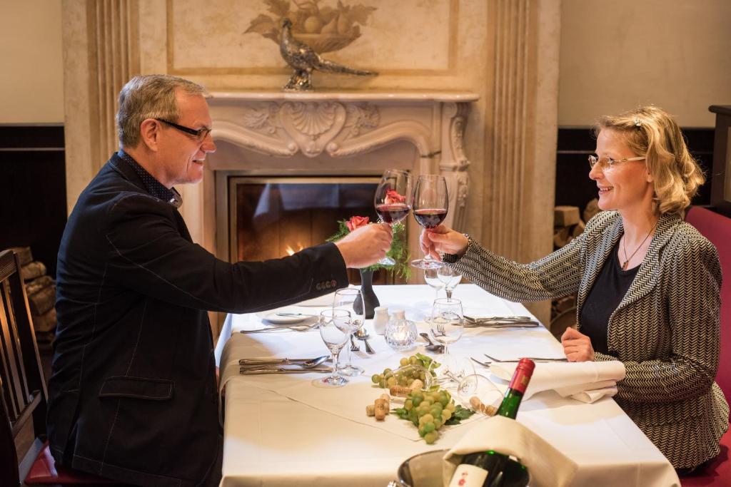 a man and woman sitting at a table with wine glasses at Hotel Goldener Löwe in Meißen