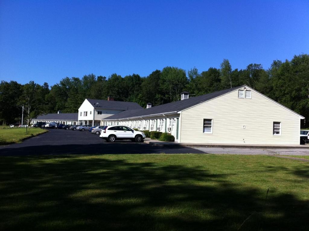 a white building with a car parked in a parking lot at Ashford Motel in Ashford