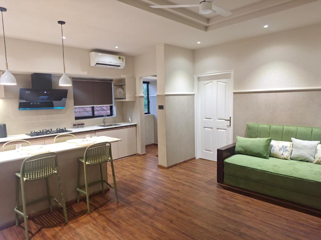a living room with a green couch and a kitchen at Gulzar 1BHK Service Apartment, kannur in Kannur