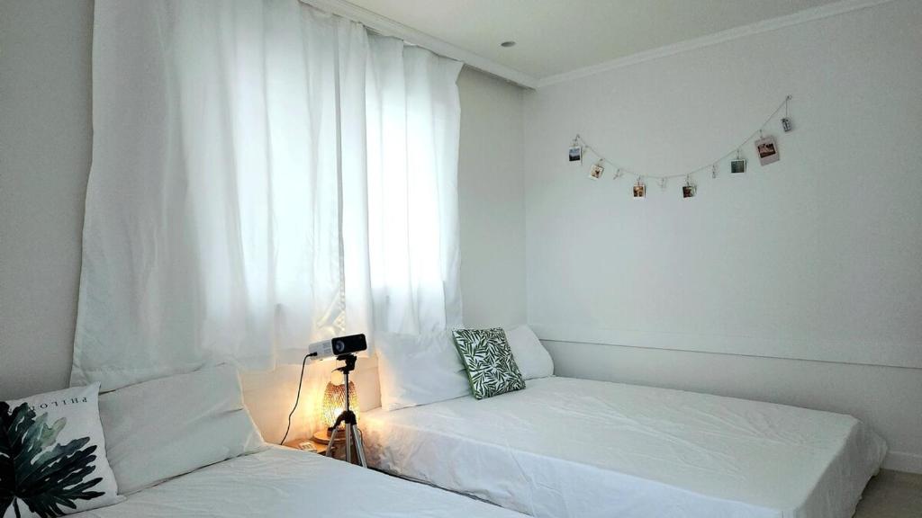 ein weißes Zimmer mit zwei Betten und einem Fenster in der Unterkunft Green Bring in Daegu