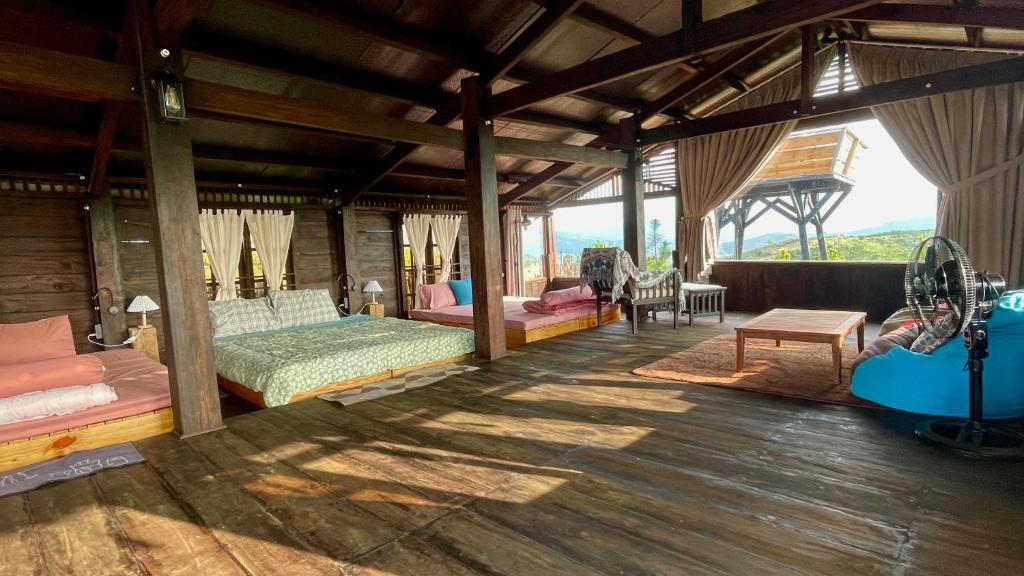 a room with several beds and chairs in it at Đen Hill Home The Wooden in Ðại Lào