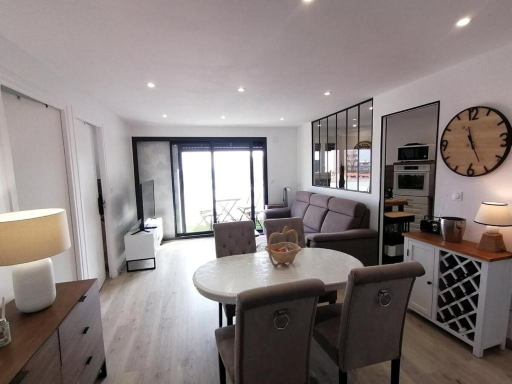 - un salon avec une table et une horloge murale dans l'établissement T3 spacieux à 150m de la plage, à Canet