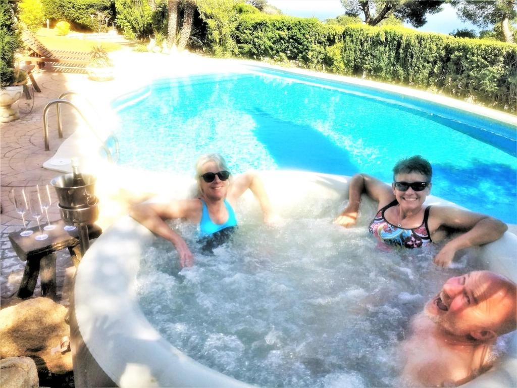 tre persone in una vasca idromassaggio in una piscina di Private Villa in Sant Feliu de Guixols Costa Brava Pool Overlooking Bay a Sant Feliu de Guíxols