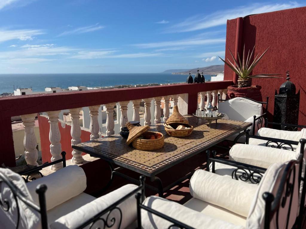 a table on a balcony with a view of the ocean at Town Gate in Tamraght Ouzdar