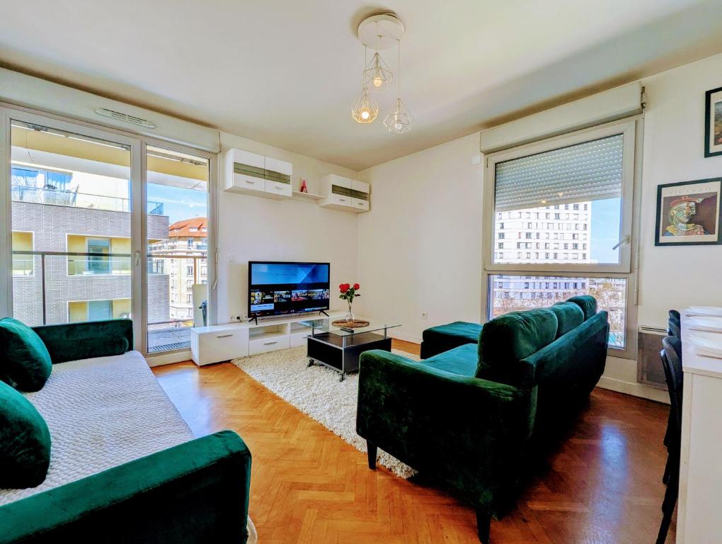 a living room with two green couches and a tv at Chic and comfortable apart with Parking and Terrace in Asnières-sur-Seine