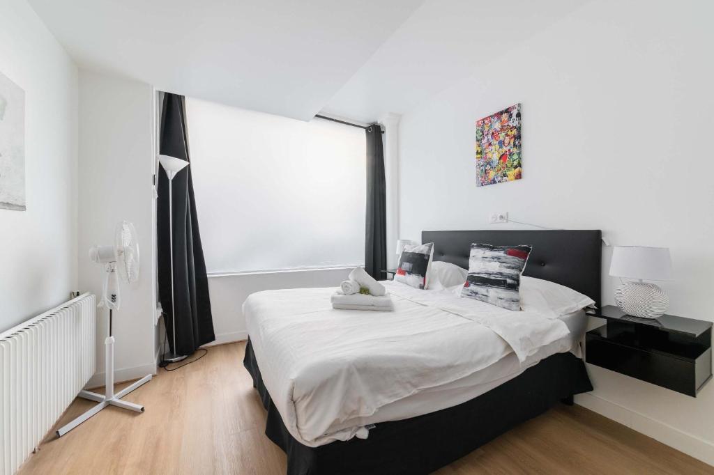 une chambre avec un lit avec des draps blancs et une fenêtre dans l'établissement Appartement Confortable Sacre Coeur - Paris 18 - 6P, à Paris