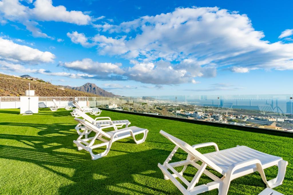 a row of white chairs on a lawn with a view at Los Menores Sea View in Adeje