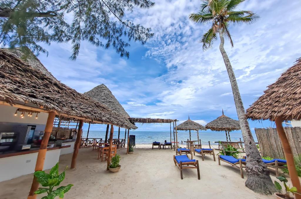 a restaurant on the beach with chairs and umbrellas at Suda Beach Lodge in Kumba Urembo