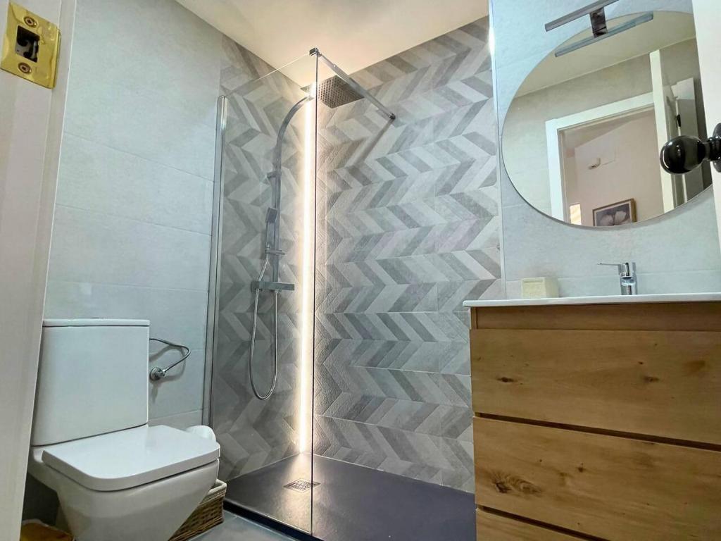 a bathroom with a shower and a toilet and a mirror at Home4u Acogedor apartamento en Maracena in Maracena