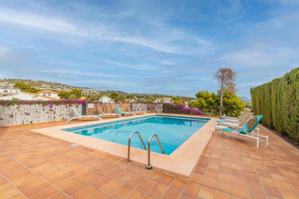a swimming pool with two lawn chairs next to a fence at La Boniquesa Bajo in Benissa