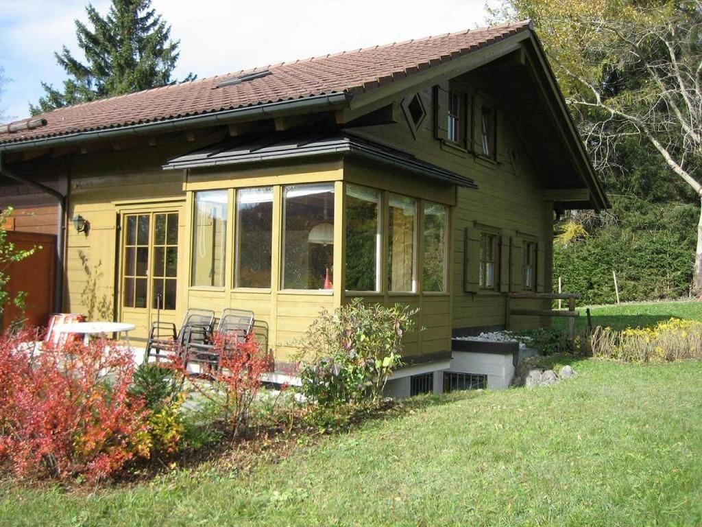 una pequeña casa amarilla con sillas en un patio en Ferienhaus im Feriendorf Reichenbach B13a, en Nesselwang