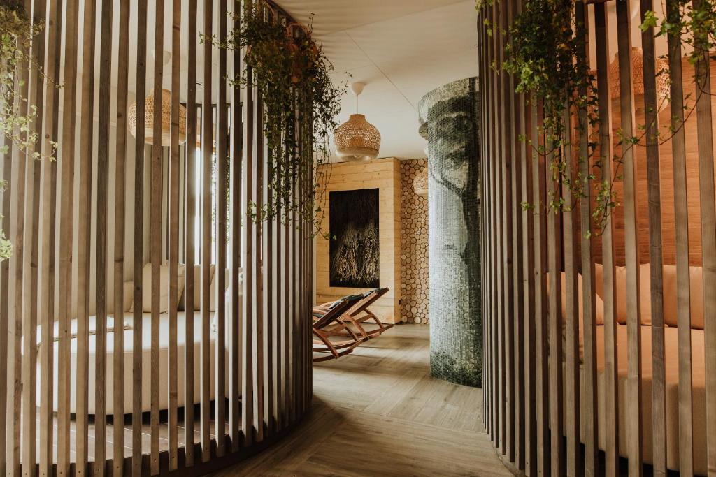 Spa relaxation area with curved wooden slats, lounge chairs, hanging plants, warm natural lighting.