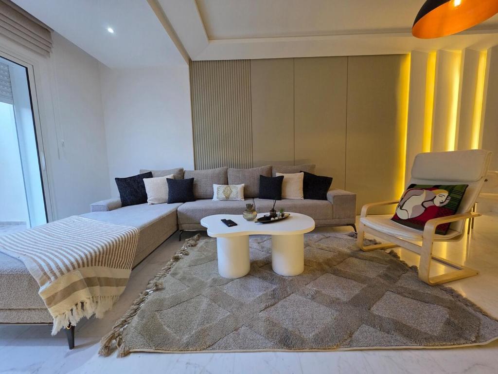 a living room with a couch and a table and a chair at appartement Sarra Mahdia in Hiboun