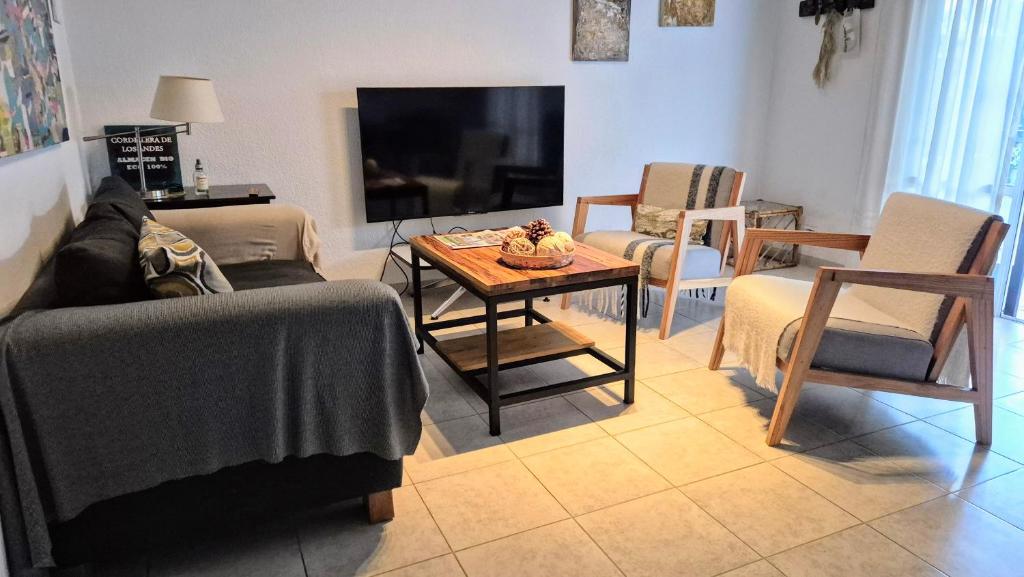 Una sala de estar con un sofá, una mesa y un televisor. en SOHO Chacras de Coria Casa Completa, en Chacras de Coria
