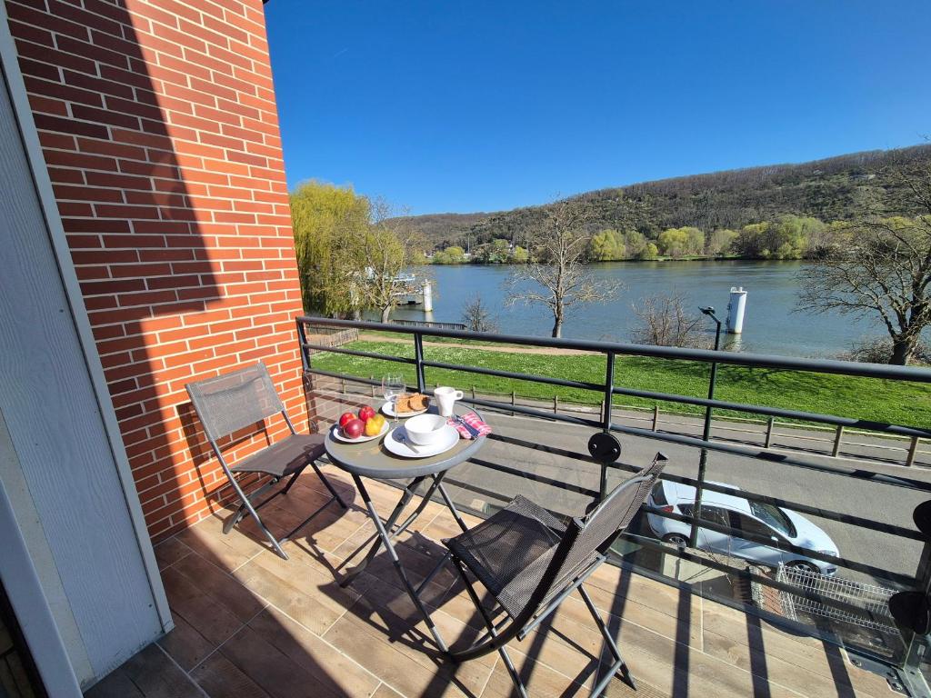 une table et des chaises sur un balcon avec vue sur une rivière dans l'établissement Balcons sur Seine - Vernon Giverny, à Vernon