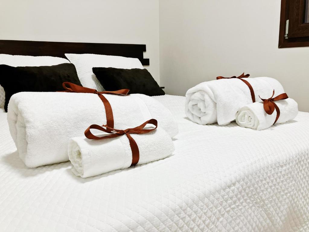 - un lit blanc avec des serviettes et un bow dans l'établissement Los Nidos de Nines, à Cabezabellosa
