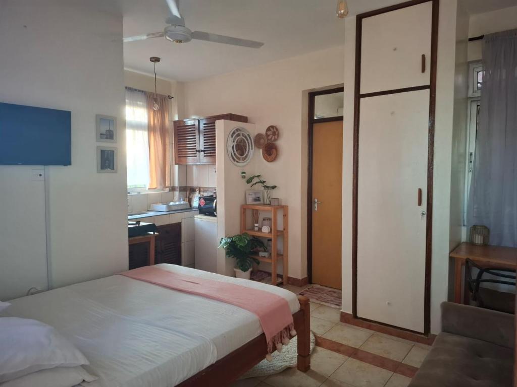 a small bedroom with a bed and a kitchen at Studio Apartment, Nyali Mombasa in Mombasa