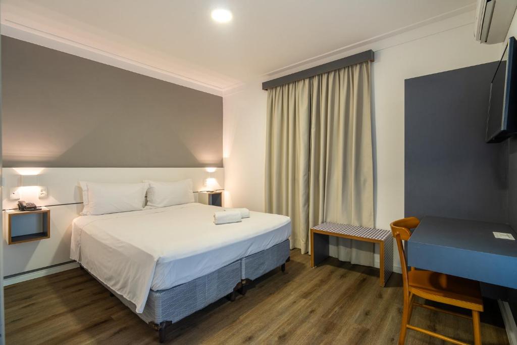 a bedroom with a bed and a desk and a television at Uniclass Hotel Lapa in São Paulo