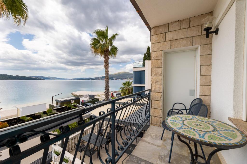 ein Balkon mit Tisch und Stühlen und Blick auf das Wasser in der Unterkunft Villa Okruk-10 meters away from the beach in Trogir