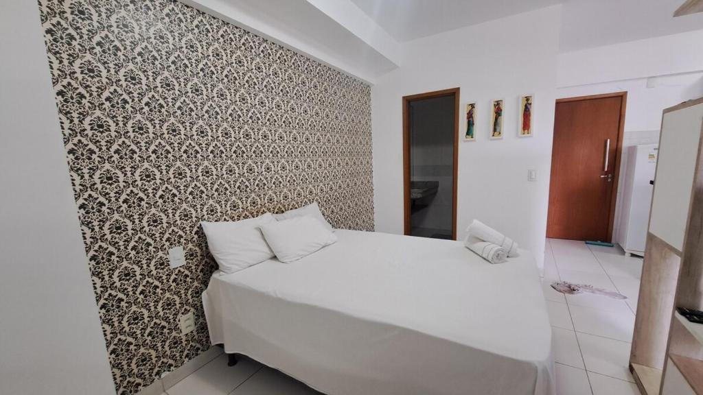 a bedroom with a white bed and a patterned wall at Santorini na rua do hospital Premium Mater Dei Piscina Academia Jacuzzi Parque Areiao e Goiania Shopping tudo perto in Goiânia