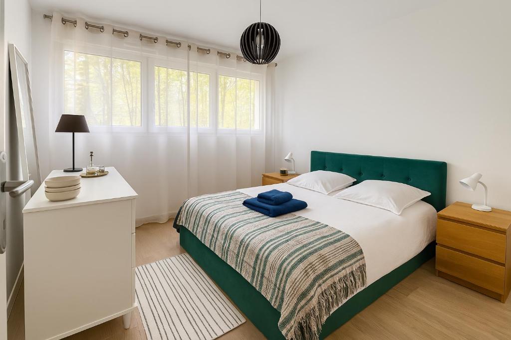 - une chambre blanche avec un lit doté d'une tête de lit verte dans l'établissement Bel appartement avec terrasse et jardin, à Vaux-le-Pénil