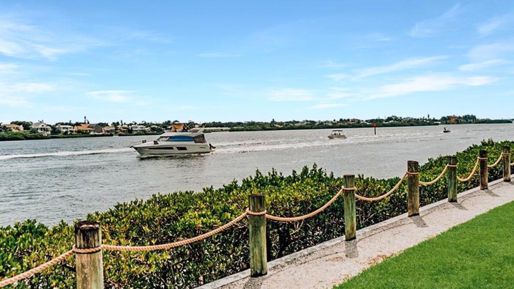a boat on a river with a fence and grass at Spacious 2BR condo on Siesta Key with private beach access in Siesta Key