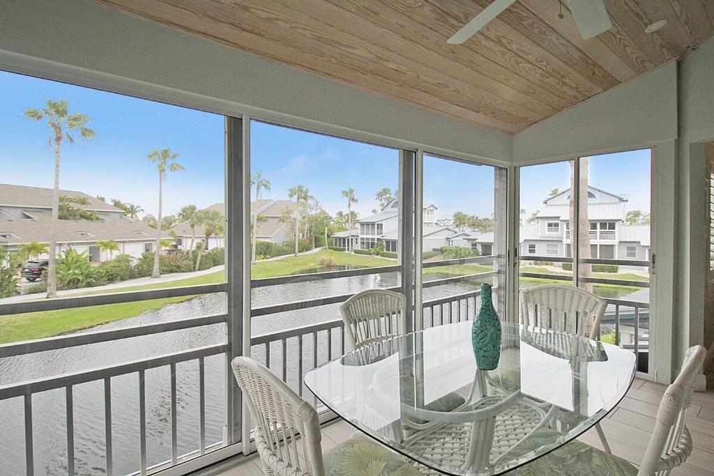 a porch with a glass table and chairs on a balcony at 2nd floor lakeview condo In Siesta Key with private beach access in Siesta Key
