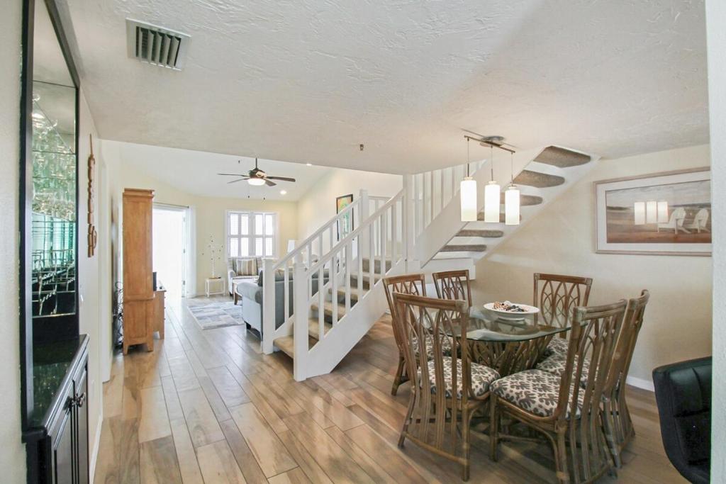 a living room with a dining room table and stairs at Spacious 3BR Siesta Key condo with private beach access in Siesta Key
