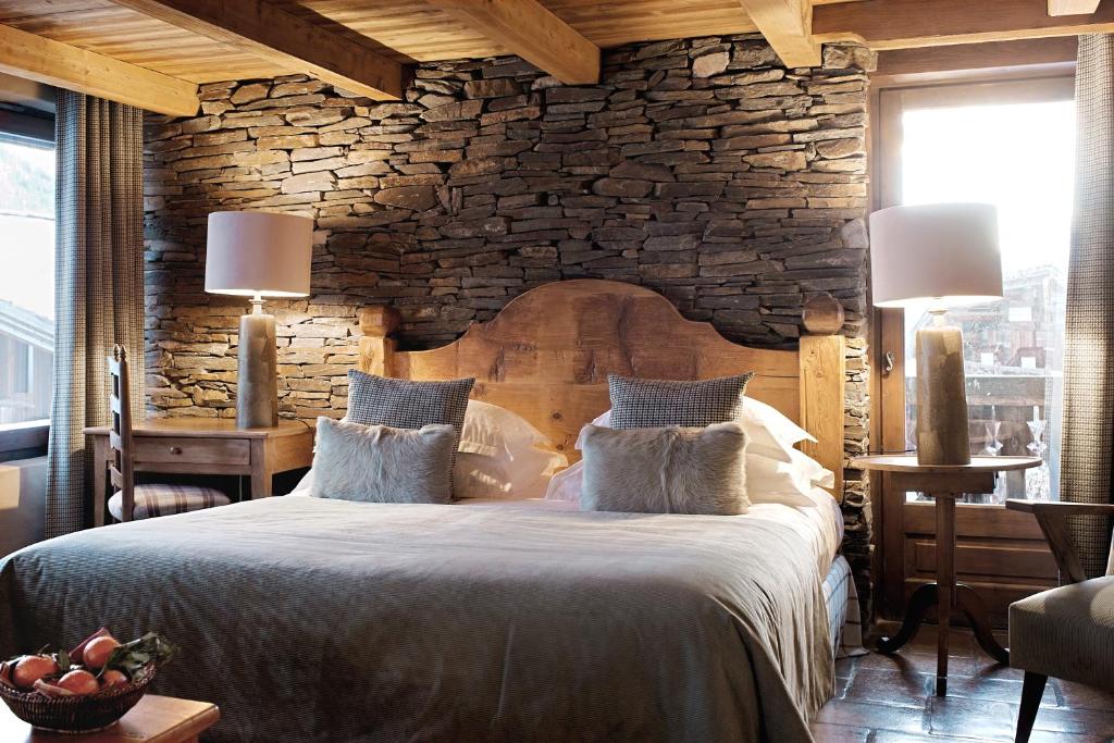 a bedroom with a large bed with a stone wall at Les Fermes de Marie in Megève