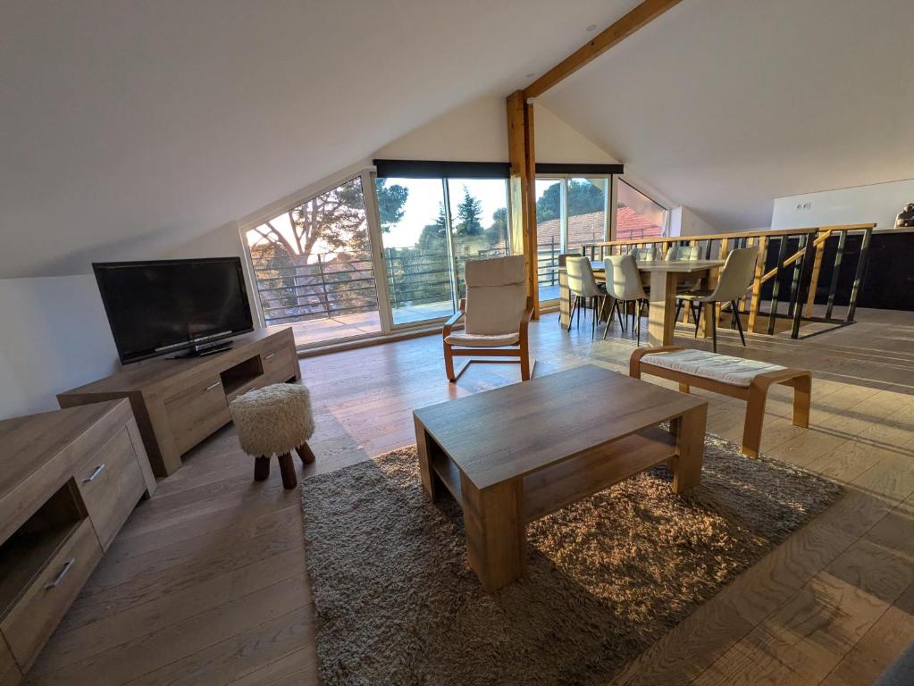 un salon avec une télévision, une table et des chaises dans l'établissement La Vigie, à Saint-Raphaël