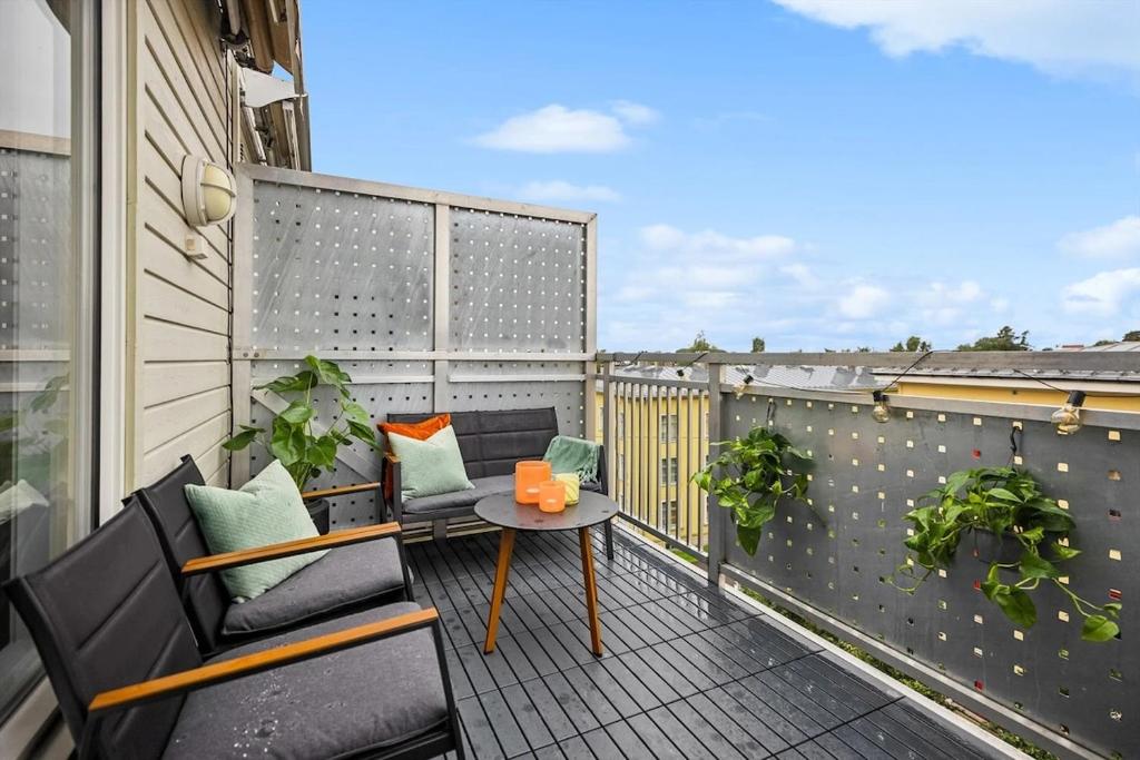 Un balcón con dos sillas y una mesa. en Modern 3 bedroom apartment - 4 minute walk from metro - top floor baclony view, en Oslo