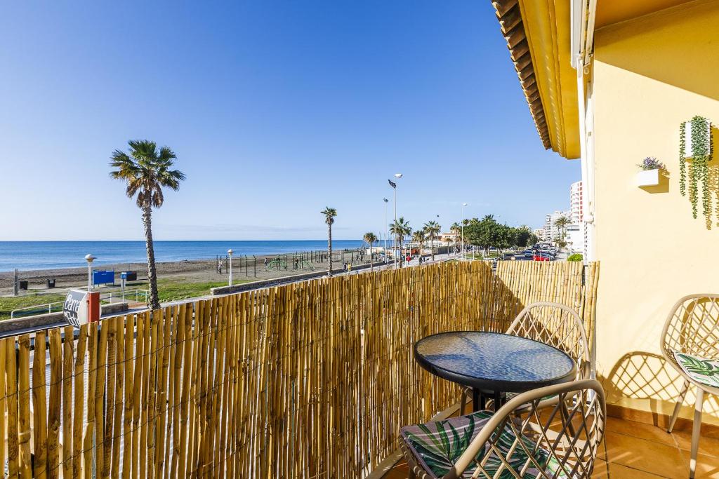 een patio met een tafel en stoelen en het strand bij A&N Los Carmenes, Torre del Mar in Torre del Mar