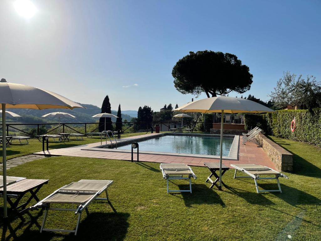 a pool with two tables and two umbrellas at Fattoria Di Pancole in San Gimignano