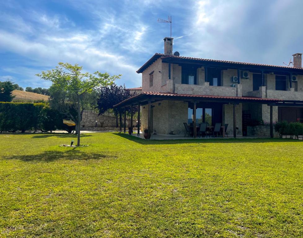 a large house with a grass yard in front of it at Artis Stone Heaven Retreat in Kalandra