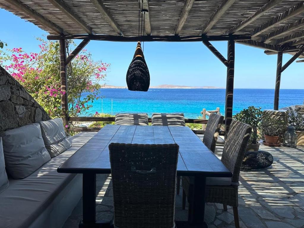 une table en bois avec des chaises et l'océan en arrière-plan dans l'établissement Villa Ipanema with Private Beach by Mykonos Mood, à Mykonos