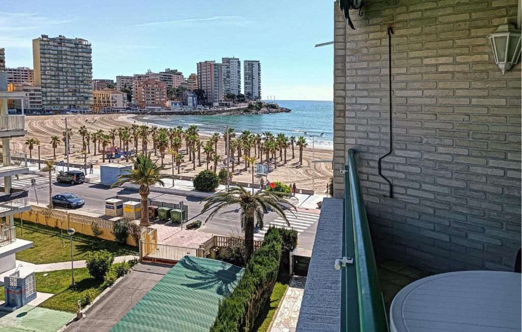 a balcony with a view of a beach with palm trees at Stunning Apartment In Oropesa Del Mar in Oropesa del Mar