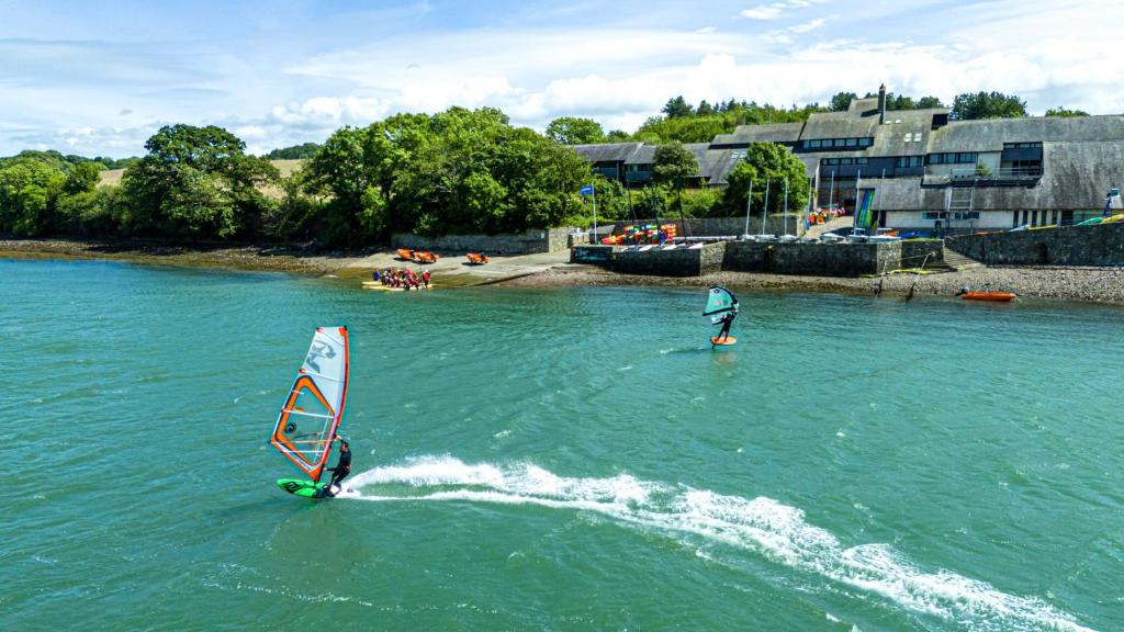 two people are windsurfing in the water at Ty Ogwen in Caernarfon