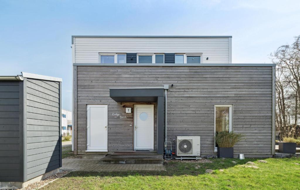 ein graues Haus mit einer Tür an der Seite in der Unterkunft Lodge Am Deich in Tossenserdeich