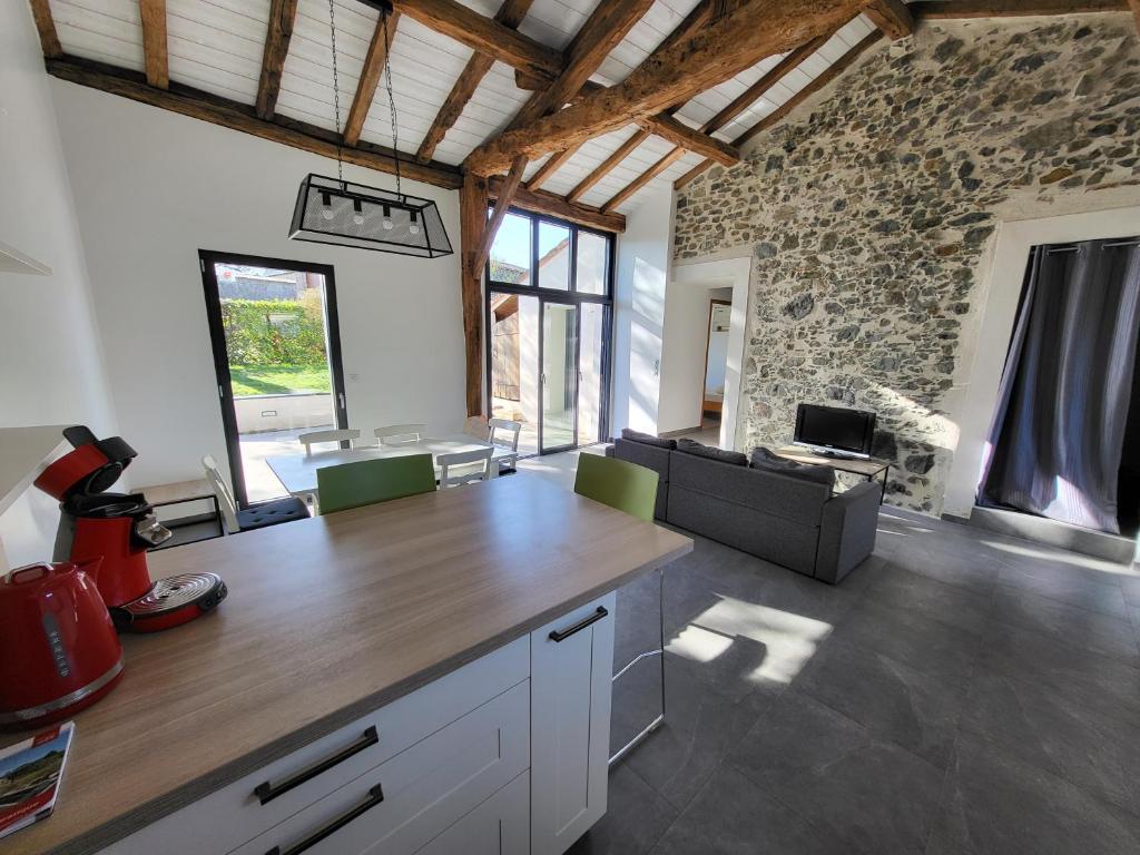 Il comprend une cuisine et un salon avec un mur en pierre. dans l'établissement La cave de la Sangueze, à Mouzillon