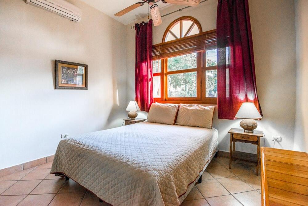 a bedroom with a bed and a window with red curtains at Melrose Suite in San Juan del Sur