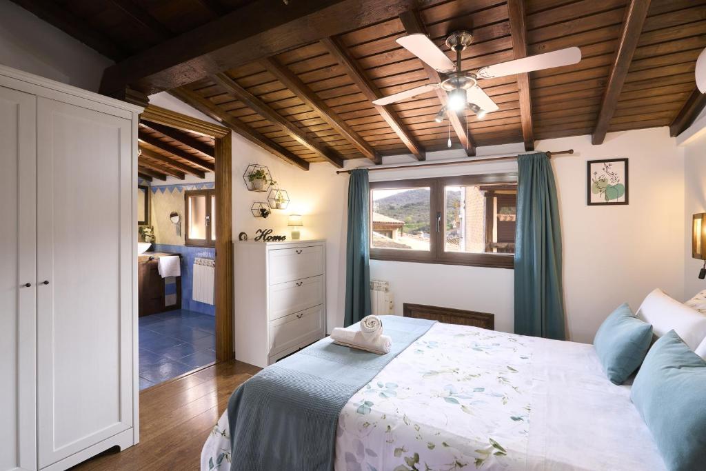 a bedroom with a bed and a ceiling fan at Apartamentos Ca' tio Celso in San Esteban de la Sierra