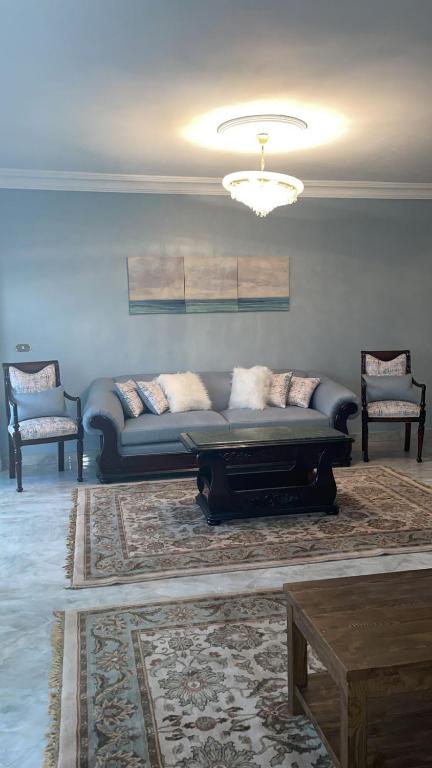 ein Wohnzimmer mit einer Couch und zwei Sesseln in der Unterkunft relax newcairo in Kairo