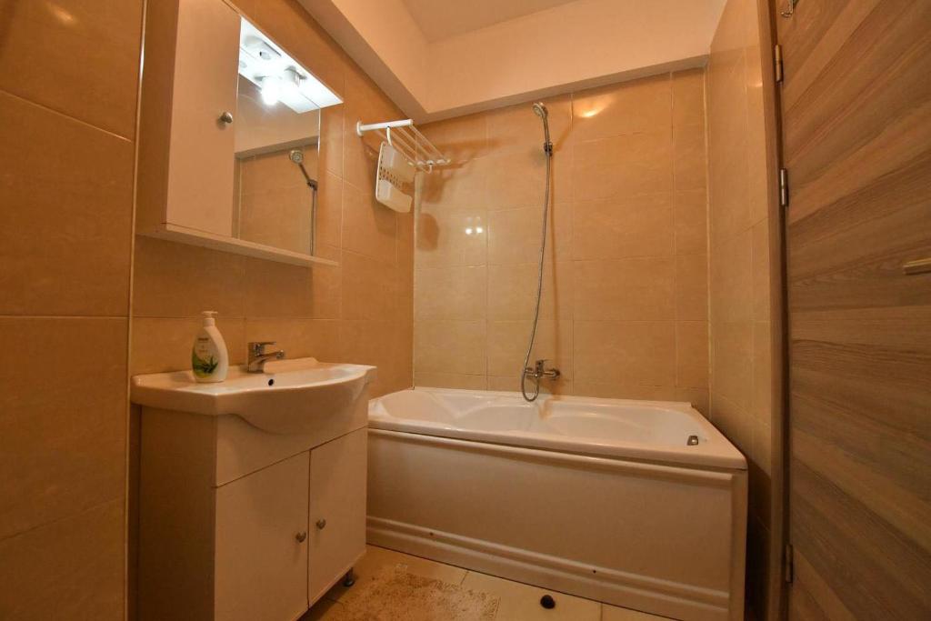 Un baño con bañera, lavabo y bañera. en Playa Apartment 3, en Mamaia